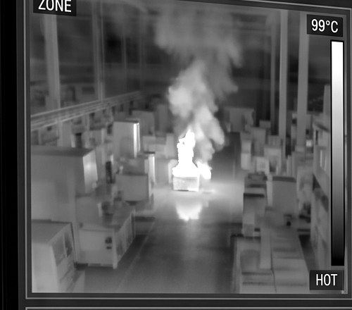 Grayscale thermal camera view of a fire risk in a warehouse